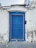 Before-and-after images showing a damaged door replaced and newly painted, framed by white trim and blue siding.