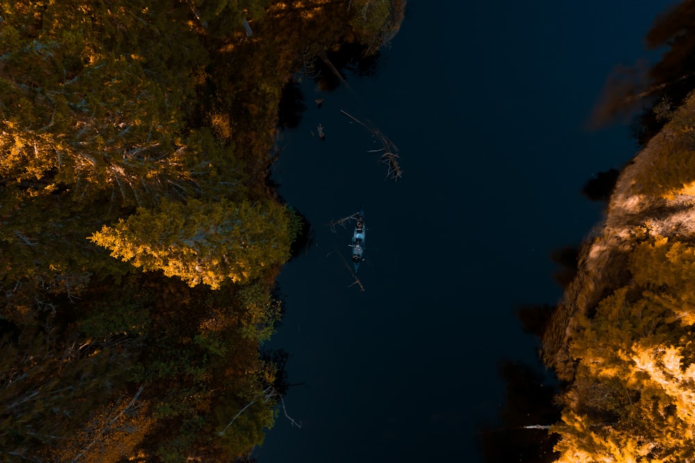 a boat floating on top of a lake surrounded by trees