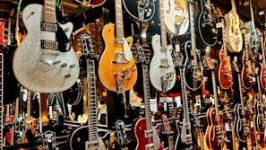 A lineup of sunvox guitars hanging on a rustic wall, each with unique finishes.