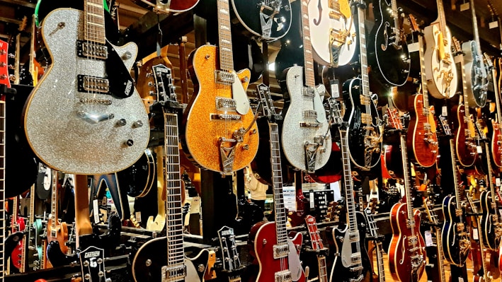 A collection of various guitars displayed on a wooden shelf.