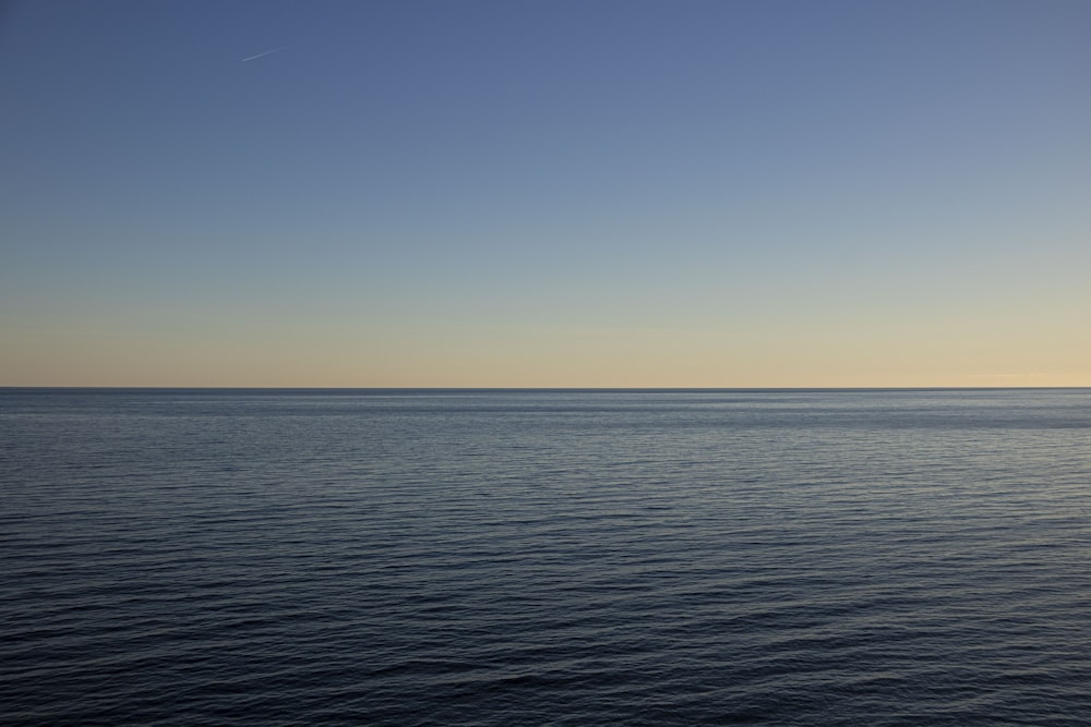 a large body of water sitting under a blue sky