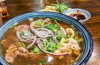 A vibrant bowl of pho served steaming hot with fresh herbs on the side.