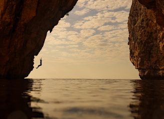 a person standing in the water in front of a cave