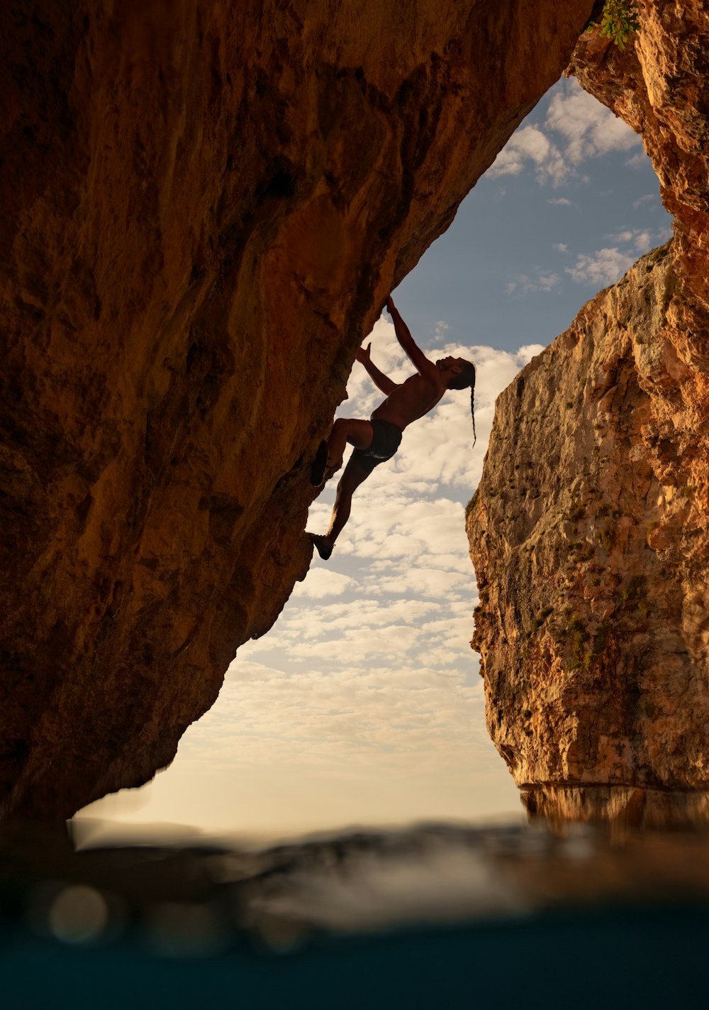 a man climbing up the side of a cliff into the ocean
