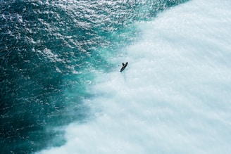 Aerial shot of a surfer riding a wave at sunrise on a beach in Região dos Lagos.