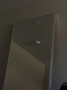 Smoke detector mounted on a ceiling in a well-lit office.