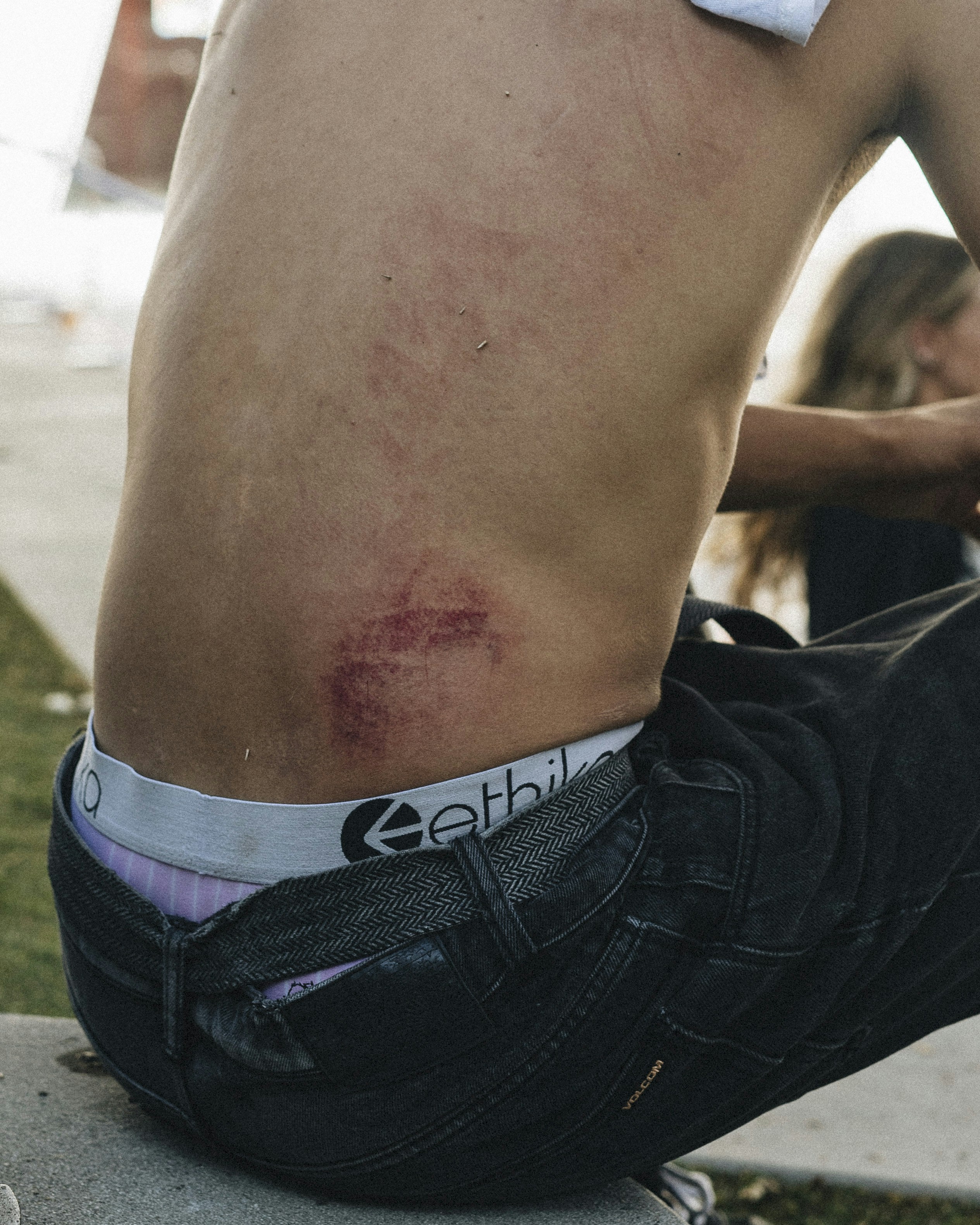 a shirtless man sitting on top of a cement slab