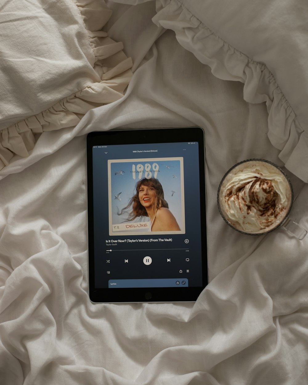 a tablet sitting on top of a bed next to a cup of coffee
