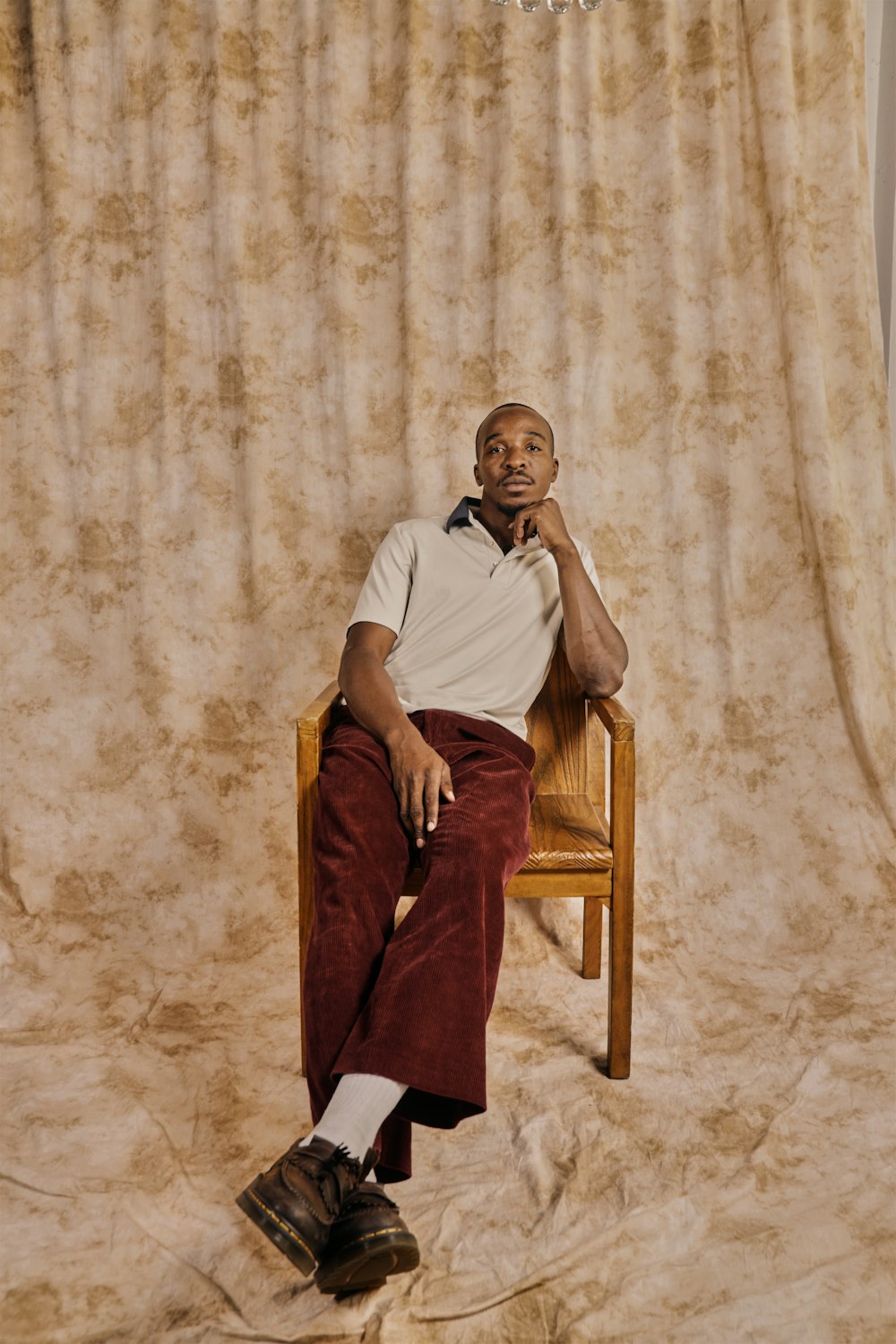 a man sitting on a chair in front of a curtain
