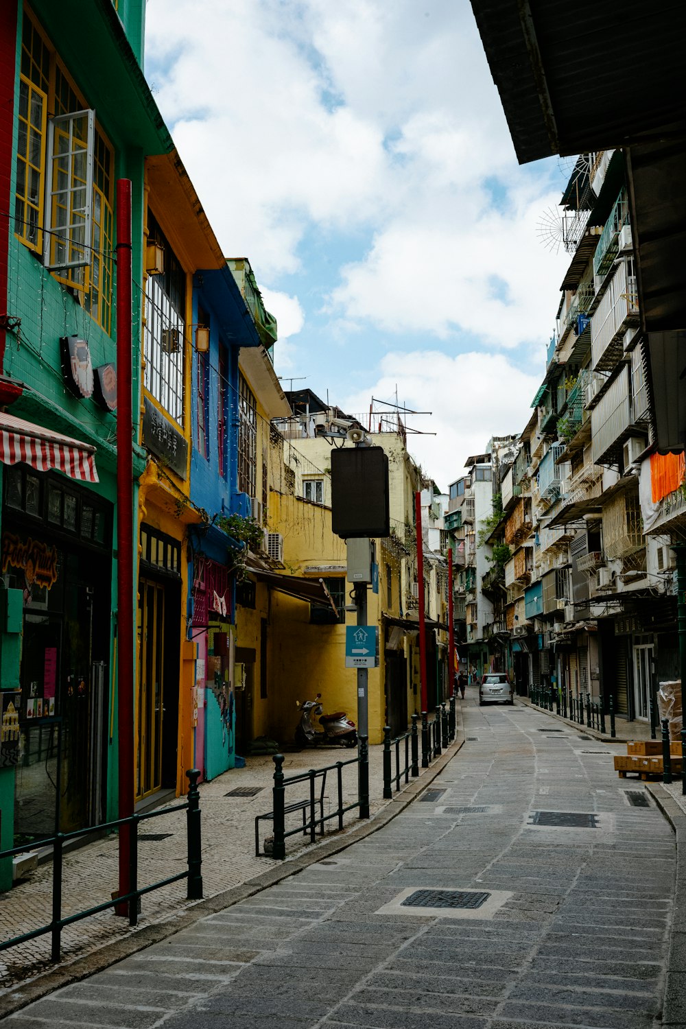 a city street lined with tall buildings under a cloudy blue sky