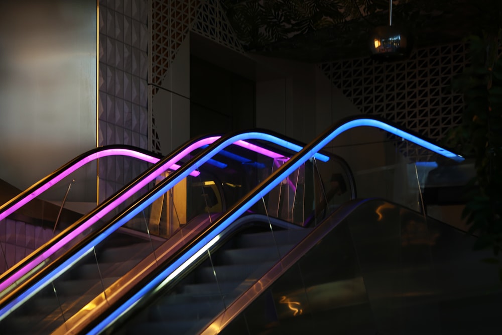a set of escalators with neon lights on them