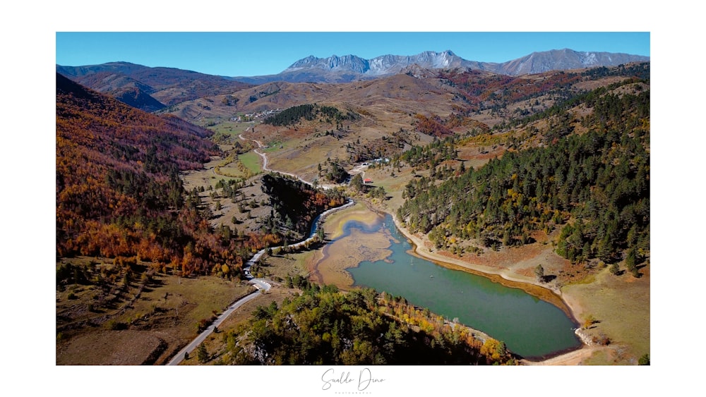 an aerial view of a valley with a lake and mountains in the background