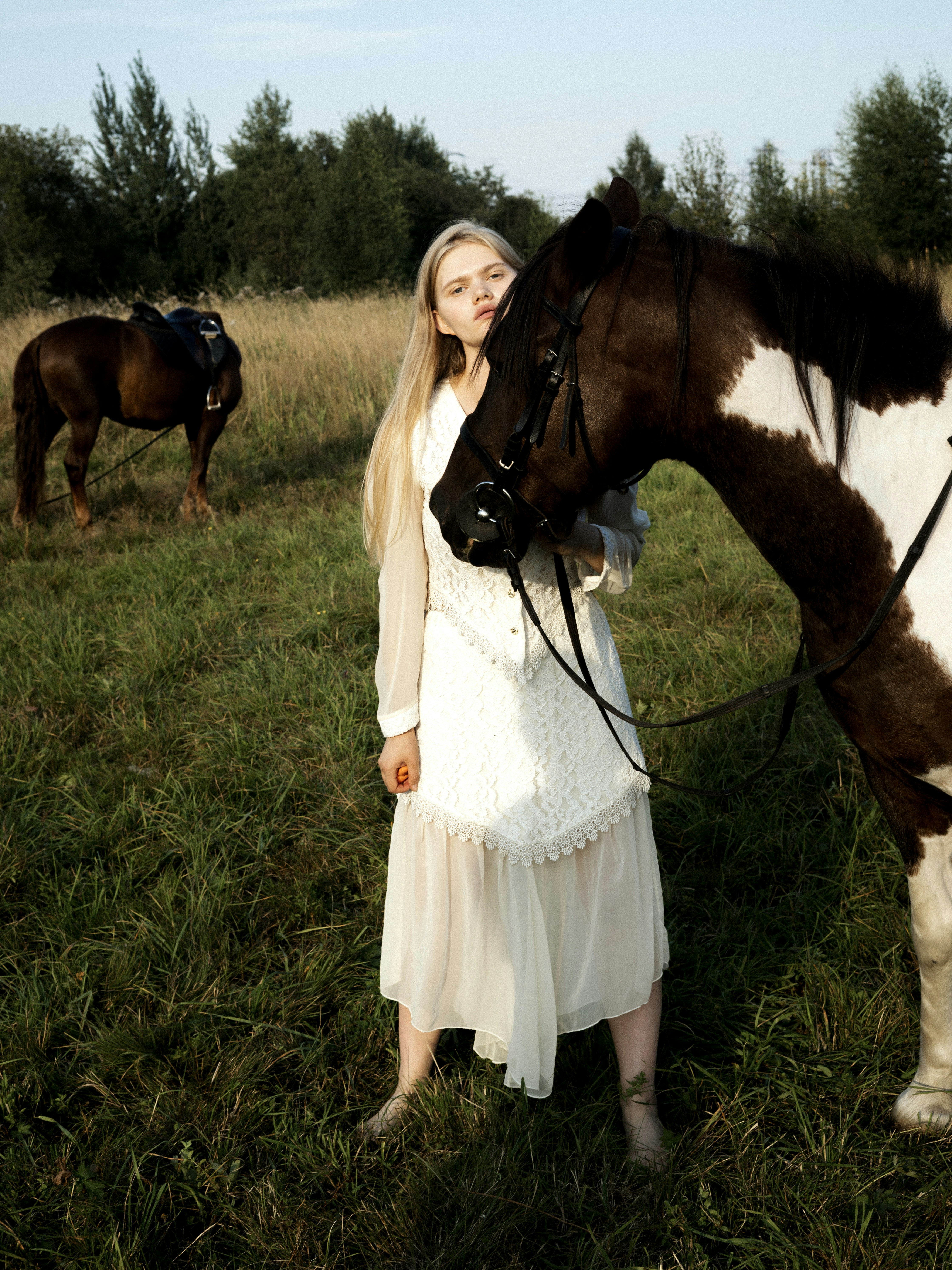 a woman standing next to a brown and white horse