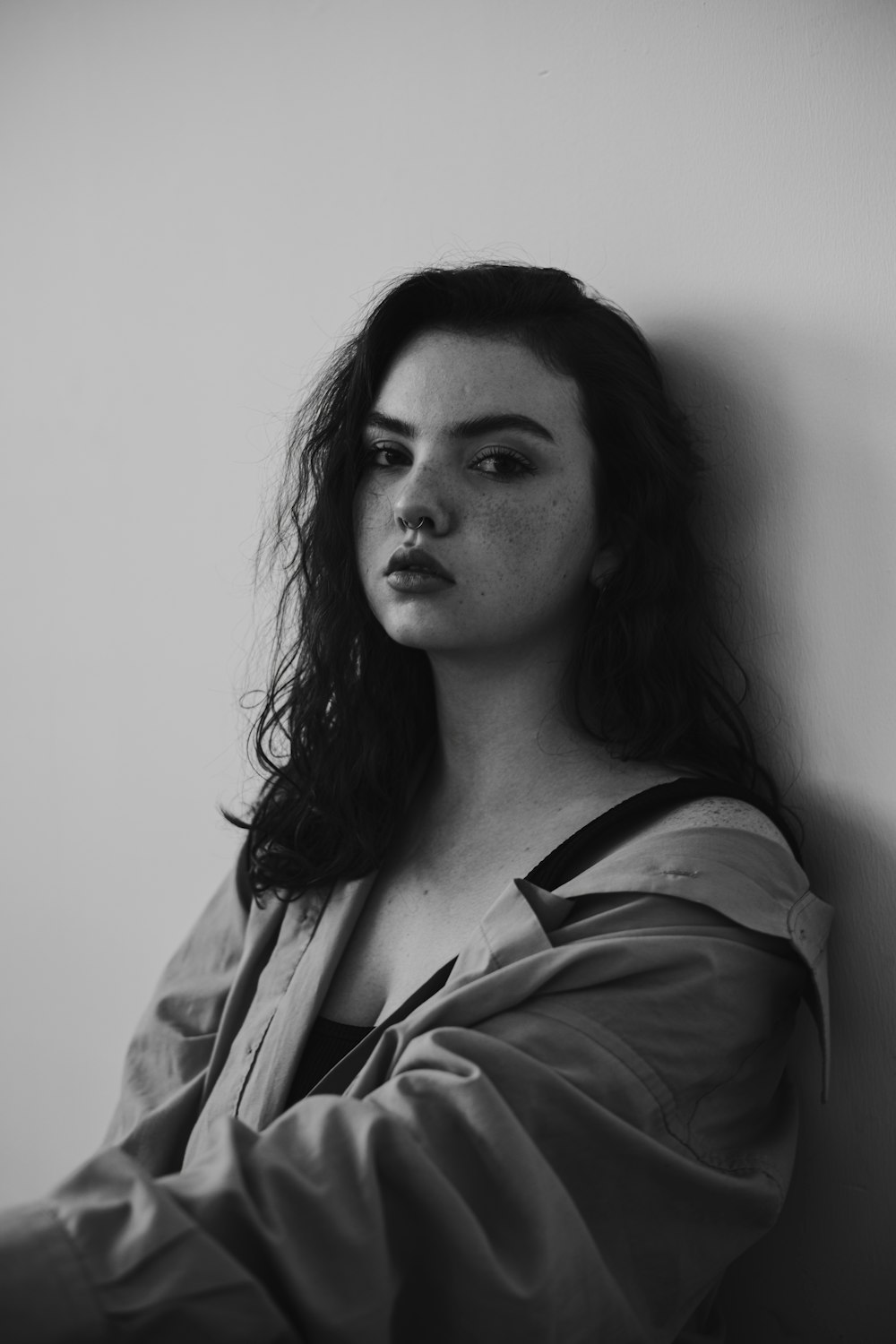 a black and white photo of a woman leaning against a wall