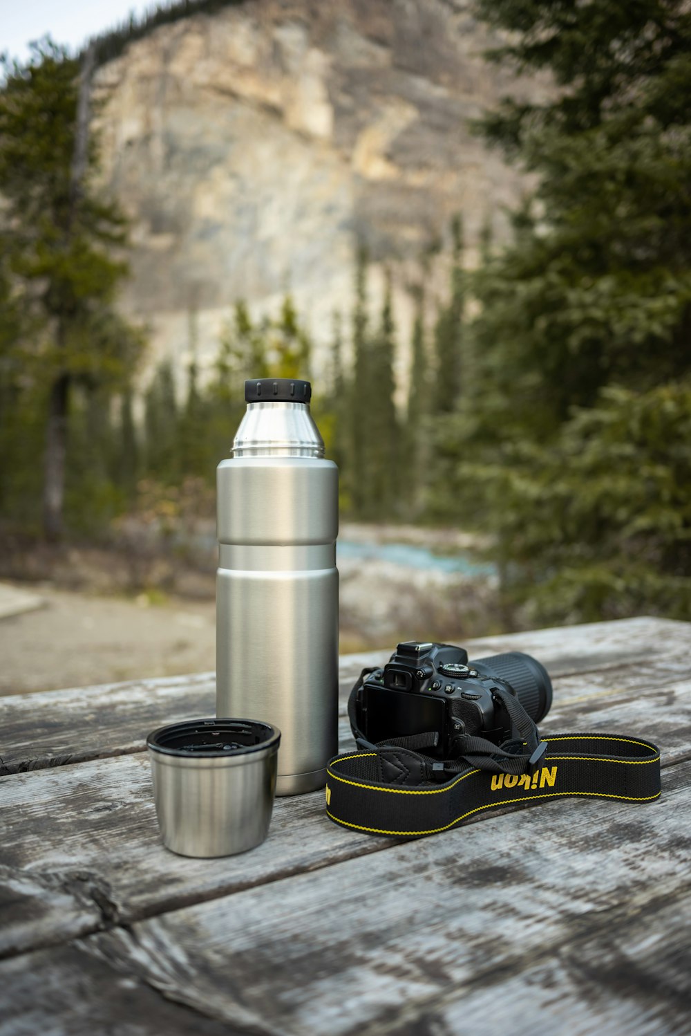 a camera and a water bottle sitting on a wooden table