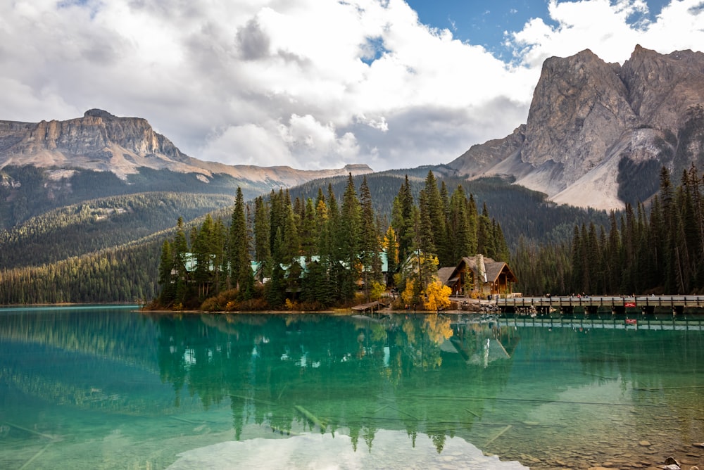 Un lac entouré d’arbres et de montagnes sous un ciel nuageux