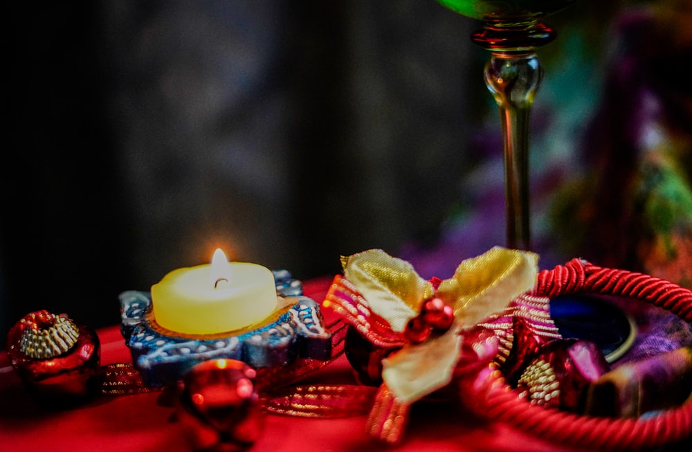 a lit candle sitting on top of a red cloth