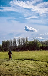 A landscaper mowing a lush green lawn under a bright blue sky.