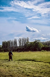 A cheerful team member trimming a lush green lawn under a bright blue sky.