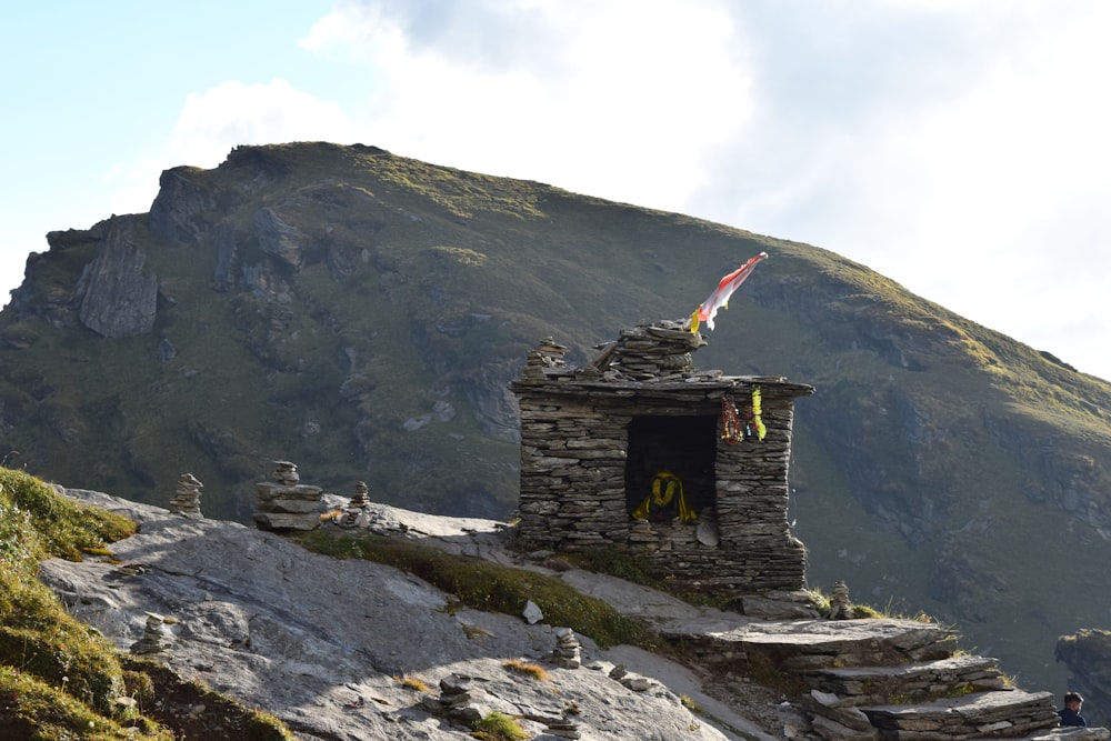 una struttura in pietra su una montagna con una bandiera in cima