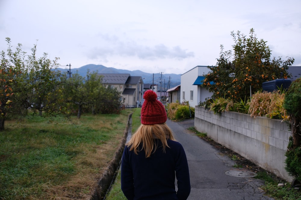 a woman in a red hat walking down a street