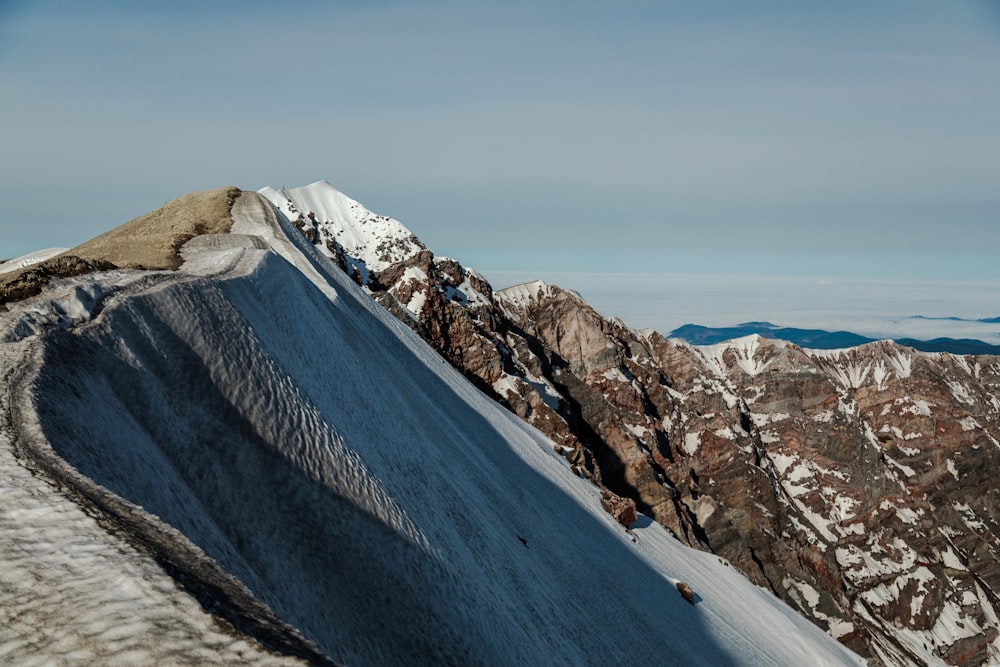 a man riding a snowboard down the side of a snow covered mountain