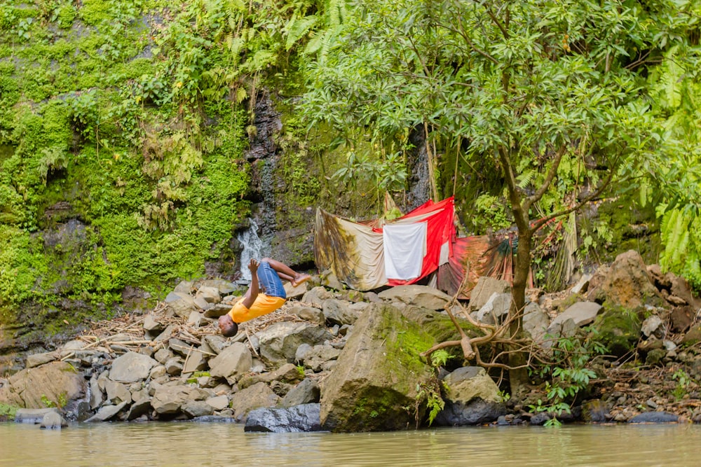 강가의 바위 더미 위에 앉아 있는 남자