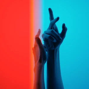 two hands reaching up to each other in front of a multi - colored background