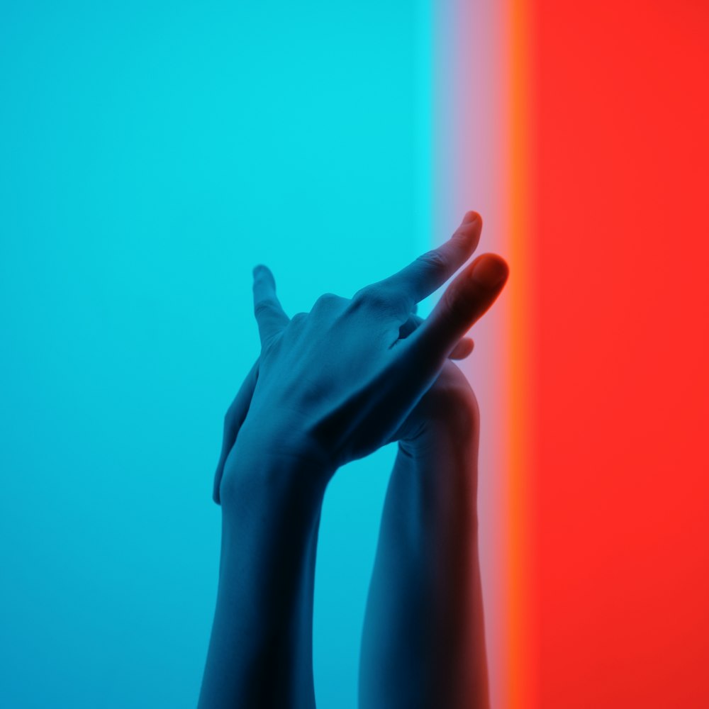 two hands reaching up against a multicolored wall