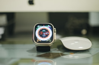 a smart watch sitting on top of a table next to a mouse