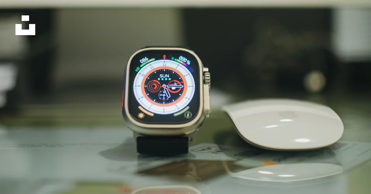 A smart watch sitting on top of a table next to a mouse photo – Free ...