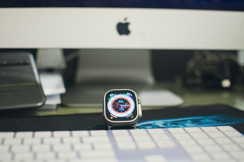an apple watch sitting on a desk next to a keyboard