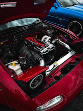 Front view of a well-maintained used car with a mechanic inspecting under the hood.