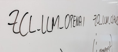 Handwritten text in black marker on a whiteboard with various words and symbols visible.