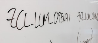 Handwritten text in black marker on a whiteboard with various words and symbols visible.