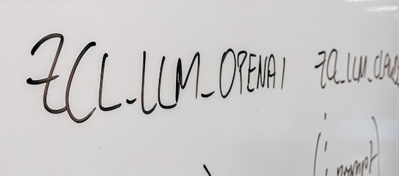 Handwritten text in black marker on a whiteboard with various words and symbols visible.