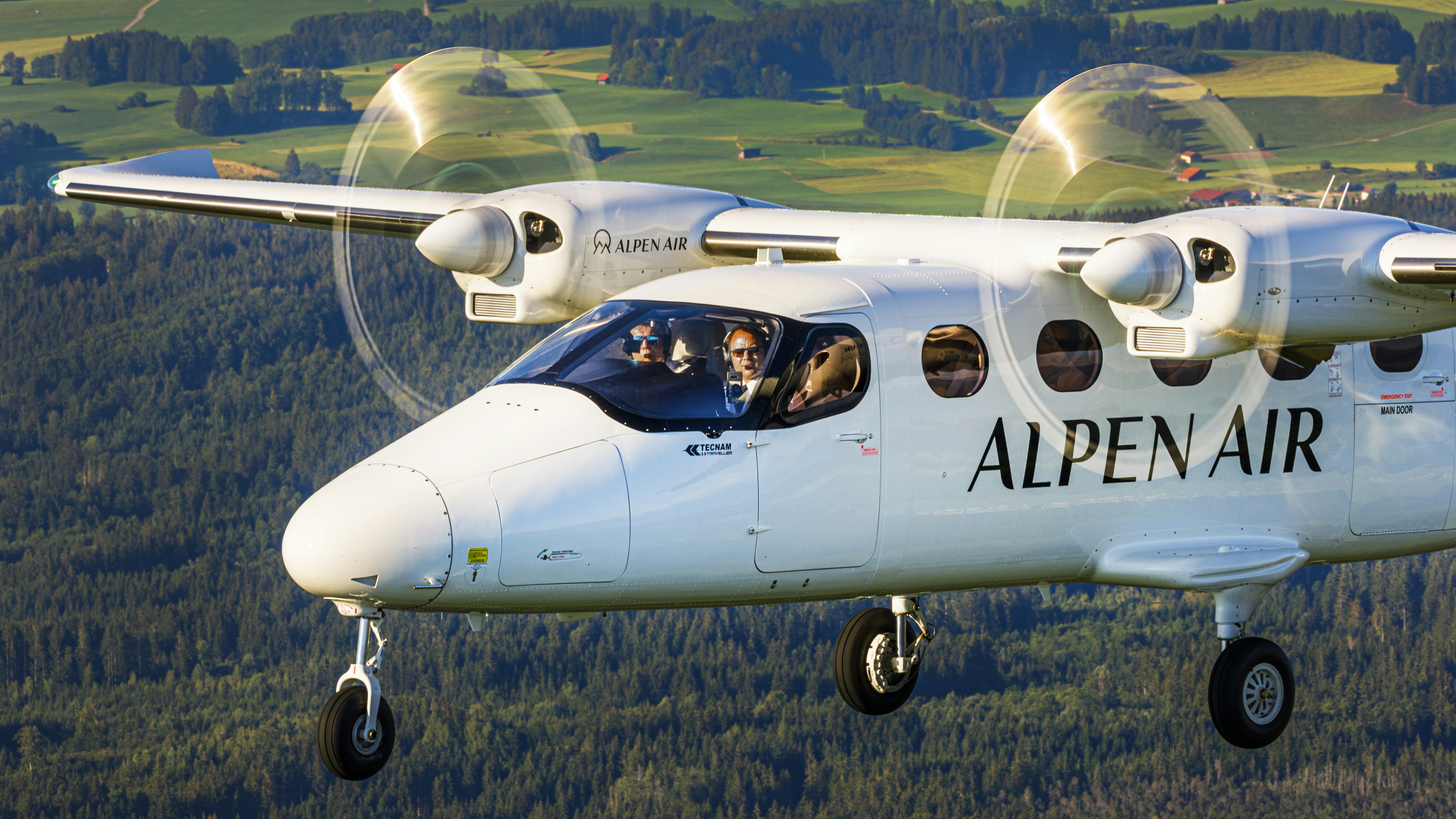 a small airplane flying over a lush green hillside