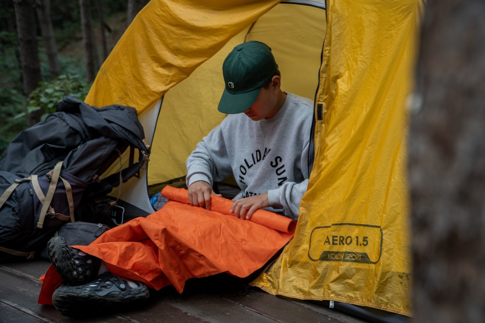 a man sitting inside of a tent next to a sleeping bag