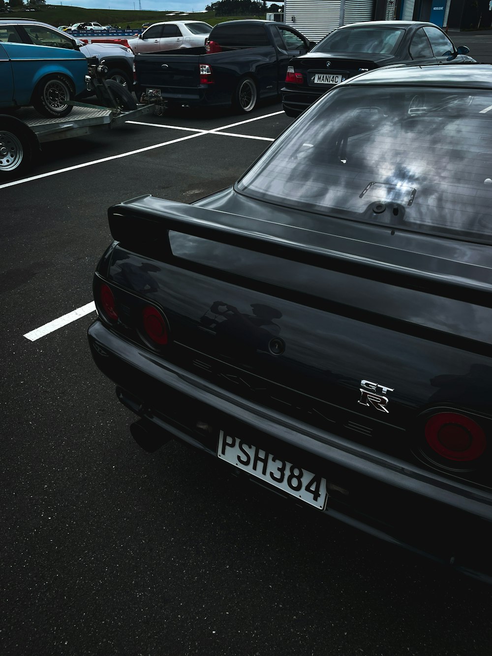 a black car parked in a parking lot next to other cars