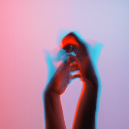 A close-up of hands mid-motion, bathed in violet and turquoise light against a deep black background.