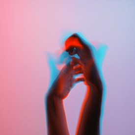 A pair of hands in motion with a motion blur effect, creating a dynamic and artistic visual. The hands appear to be set against a gradient background with hues of pink and light blue, giving a sense of fluidity and expression.