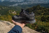 a person holding a shoe on top of a mountain