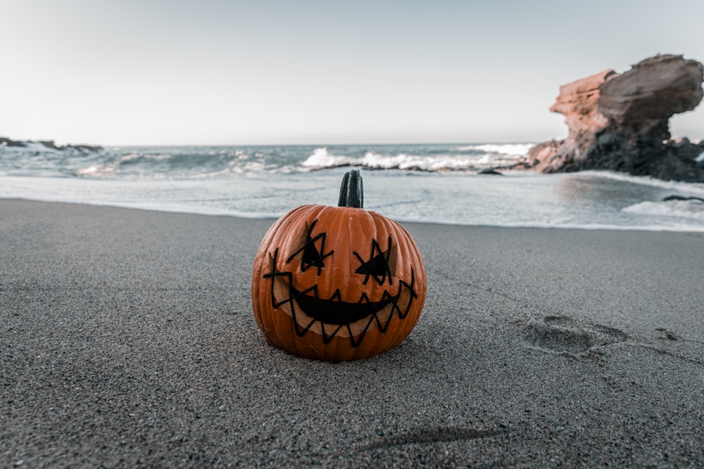 a carved pumpkin sitting on top of a sandy beach
