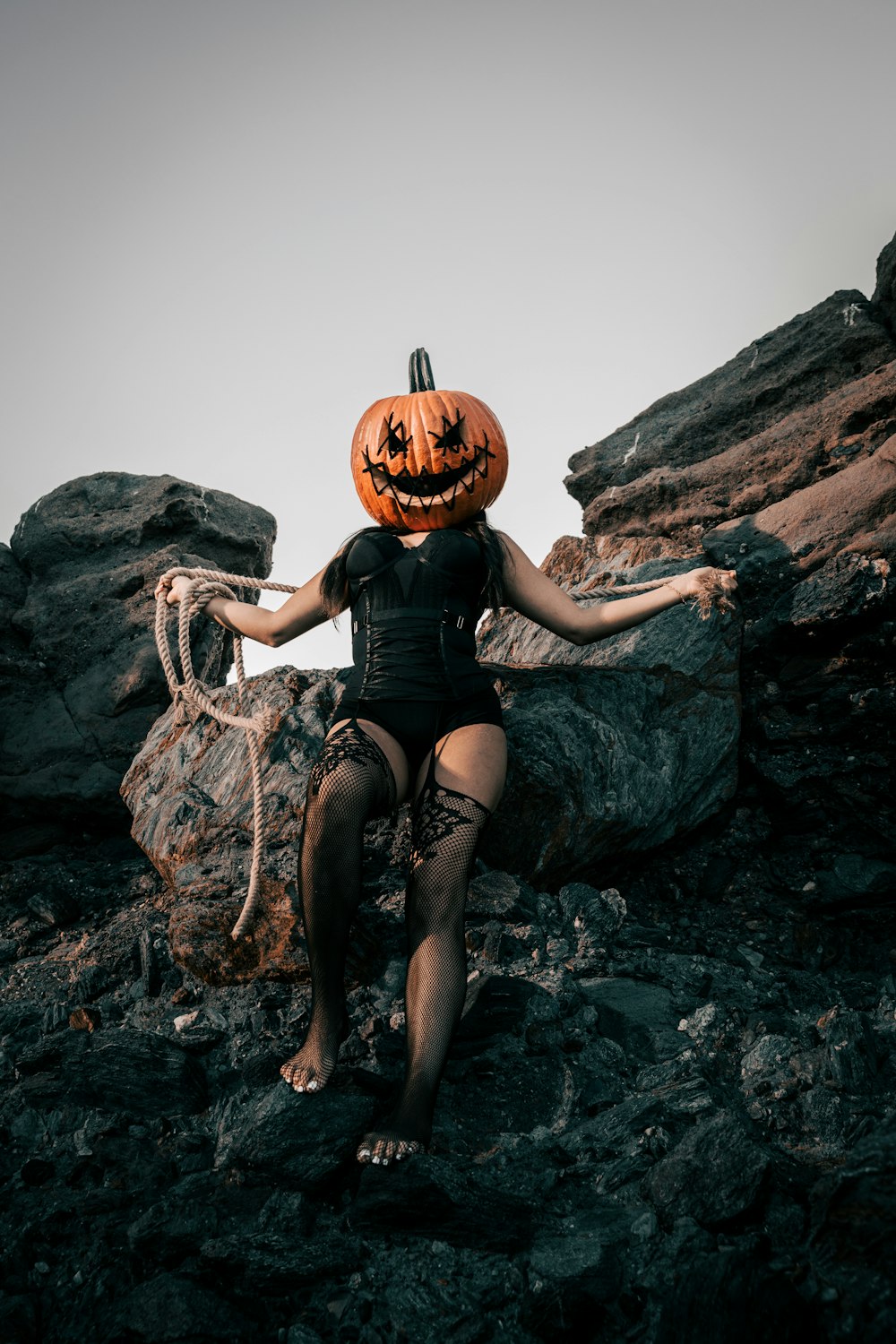 a woman sitting on a rock with a jack - o - lantern on her head