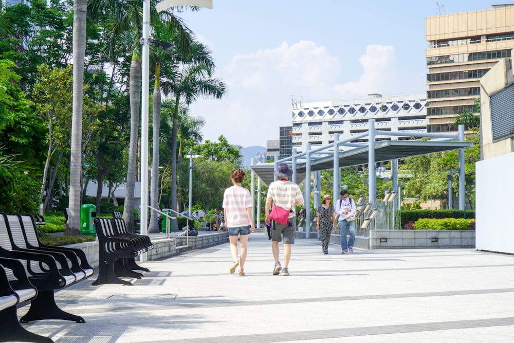 a group of people walking down a sidewalk next to benches