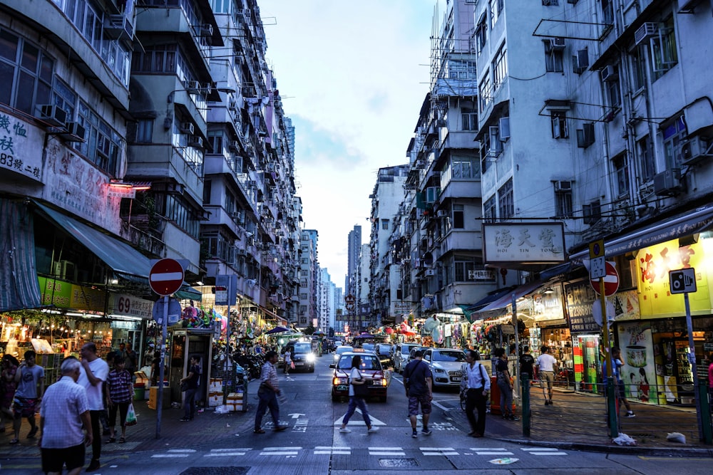 a group of people walking down a street next to tall buildings