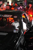 A driver focused inside a drift car cockpit with racing gear.