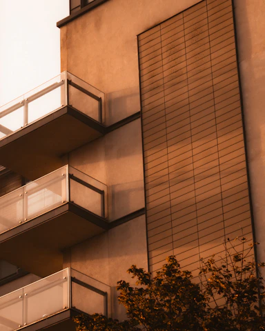 Fachada moderna de un edificio rehabilitado con balcones y ventanas que reflejan la luz del atardecer