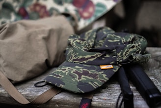 Close-up of camo-patterned gear resting on a mossy log in the woods.