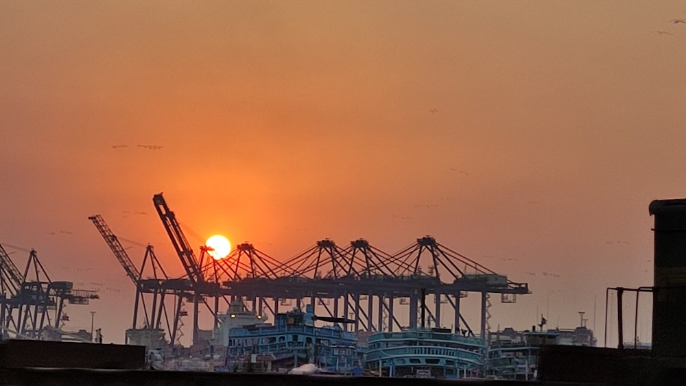 the sun is setting behind a large crane